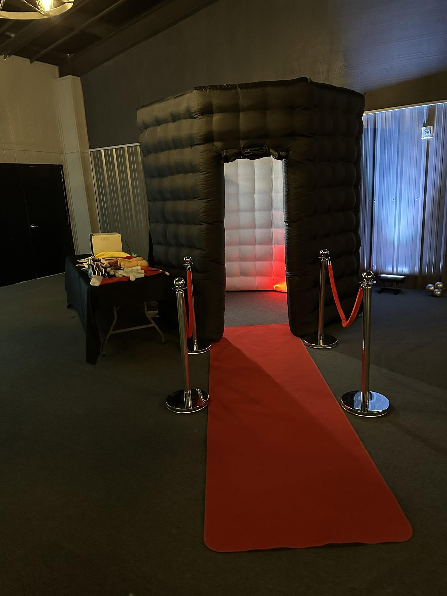 Enclosed photo booth setup indoors with red carpet